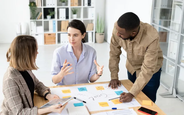 Team brainstorming around a goal map with sticky notes during an ideation session